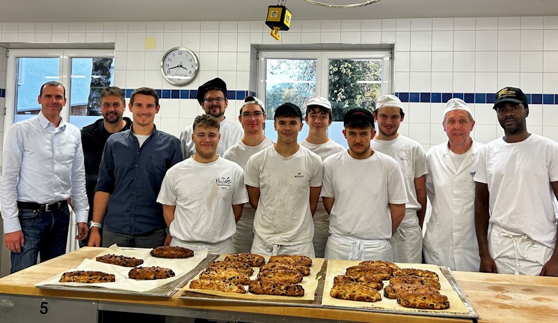Schüler, Schulleiter und Lehrer vor Stollen in der Backstube