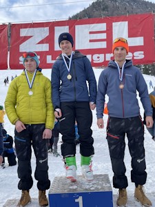 Drei Schüler im Winter auf dem Siegerpodest, dahinter ein ZIEL Transparent.