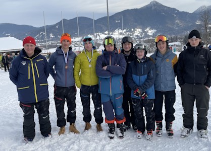 Eine Gruppe Jugendlicher, teilweise mit Helm, stehen im Schnee.