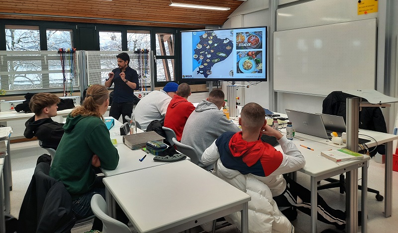 SchülerInnen in einem Klassenraum vor einem Bildschirm