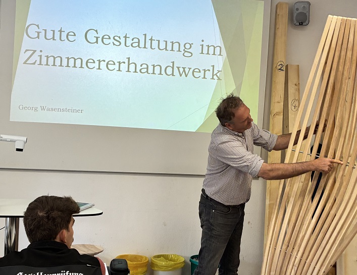 Mann zeigt auf hölzernes Werkstück vor Beamer